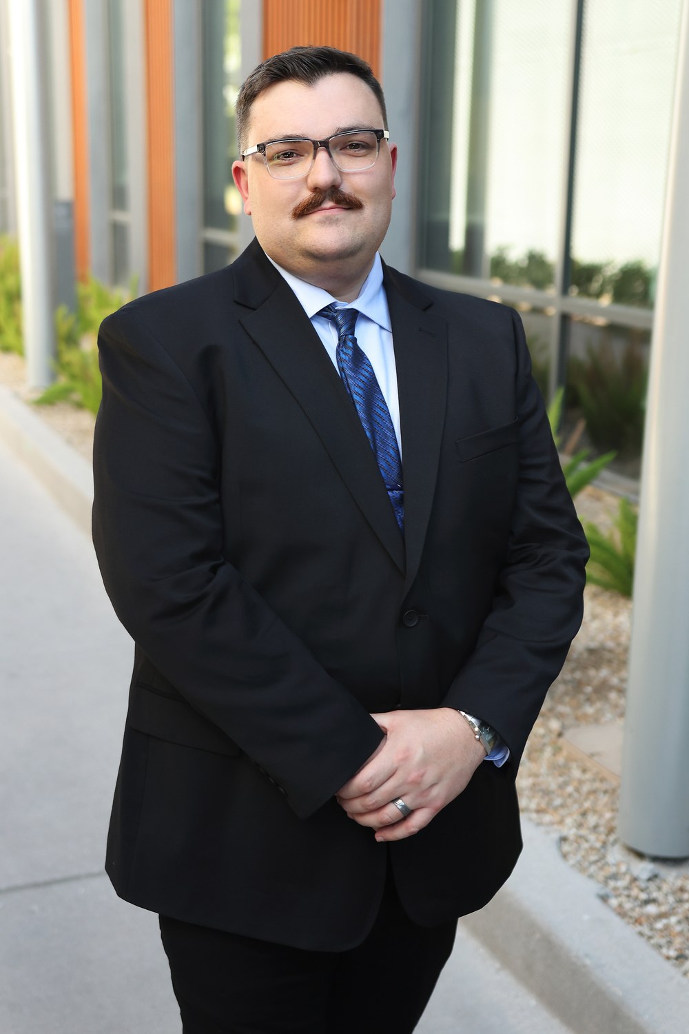 Ace Ayres, Office Manager and Paralegal at Summit Trial Attorneys, in a suit outdoors