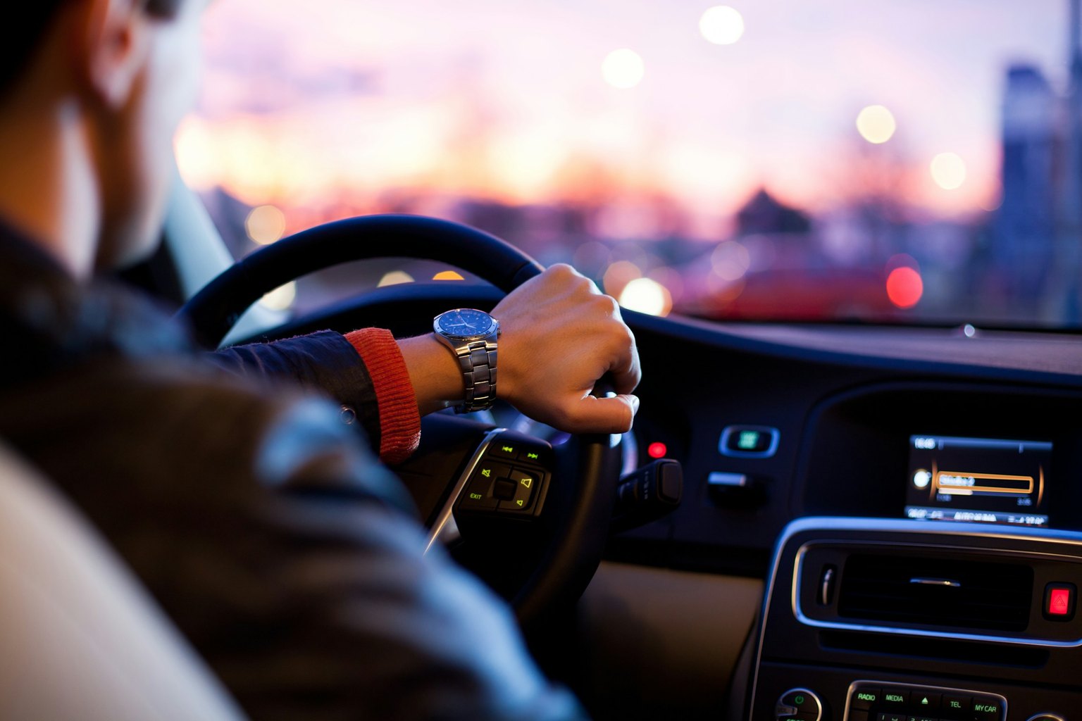 Driver's hands on a steering wheel at dusk, a scene a Las Vegas Uber & Lyft accident lawyer may review after a rideshare accident